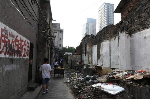 墙上的标语“旧村不拆隐患多，搬迁上楼福满园”，拆迁户笑不起来